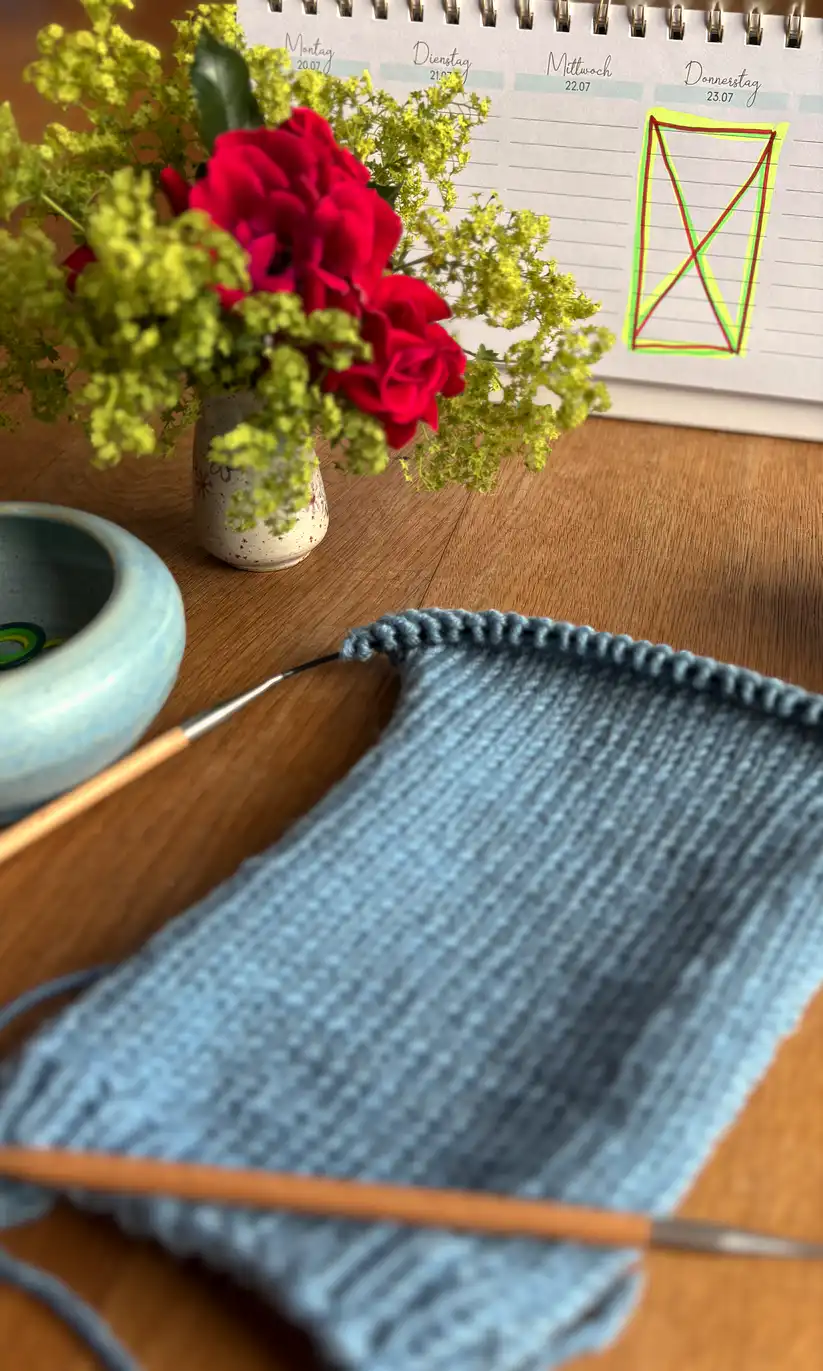 Kalender mit Markierung für einen Kurstermin mit Strickzeug und Blumen