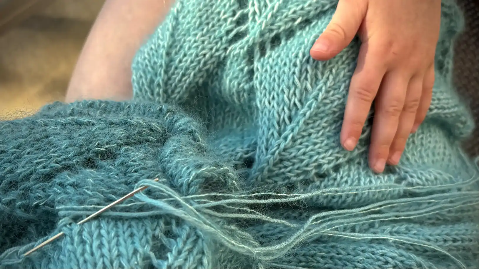 Blauer Strickpullover wird zusammengenäht