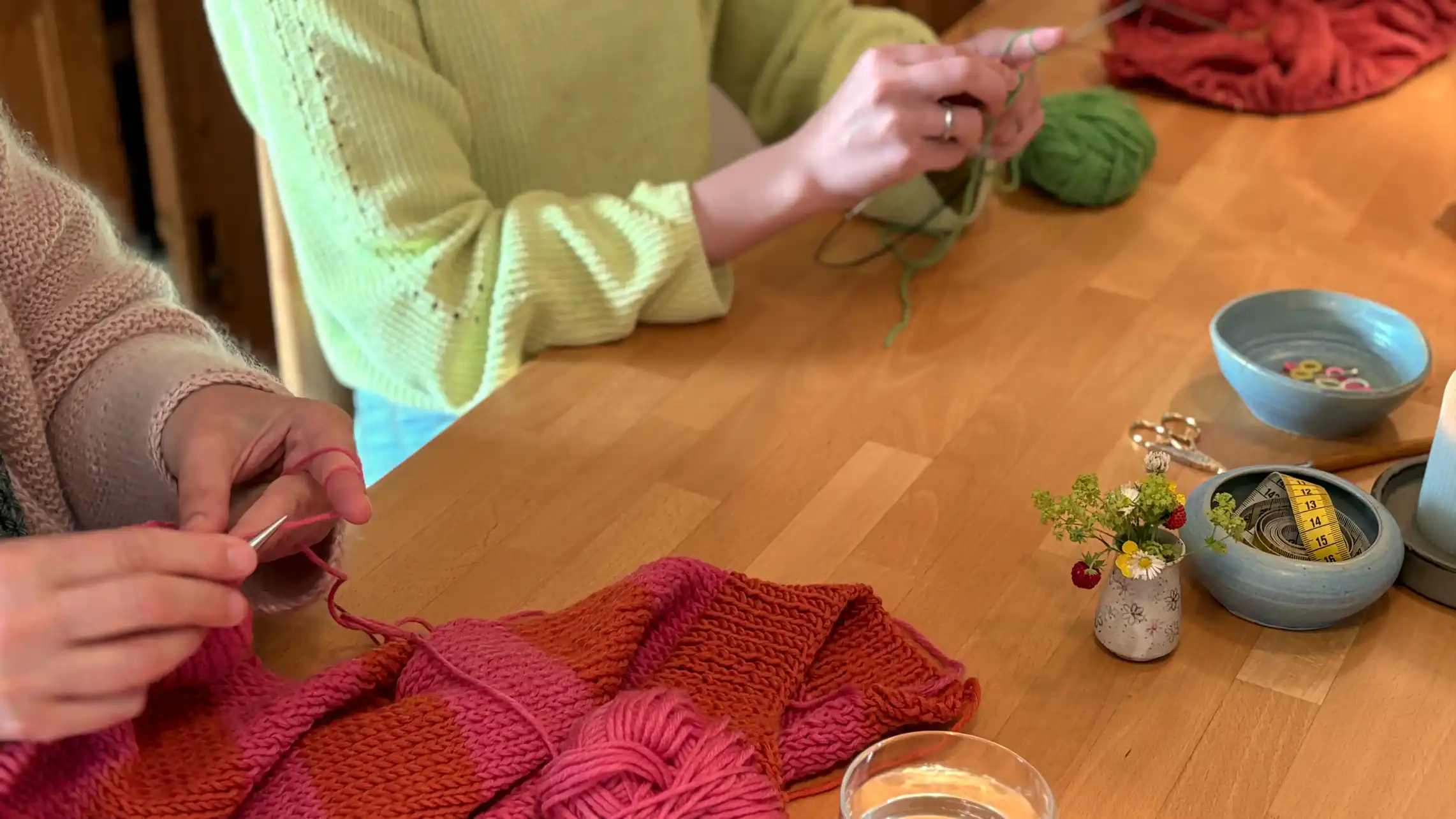Frauen sitzen am Tisch und stricken gemeinsam